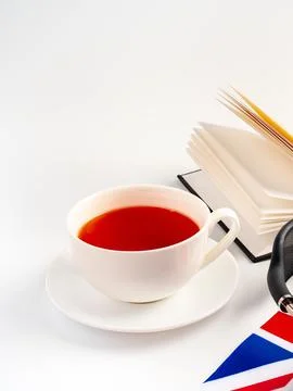 Cup of tea on a white table with a book and a flag in the background Stock Photos