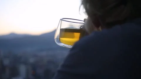 A cup of tea in a woman's hand against the blurred background of a sleeping city Stock Footage 321527733