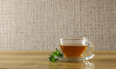 Cup of tea on a wooden table with mint leaves beside it in a simple setting Stock Photos