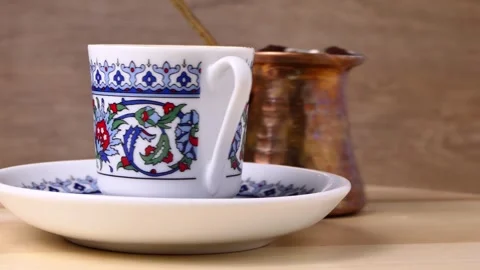 A cup of Turkish coffee and copper coffee pot rotate on a board Stock Footage 248322716