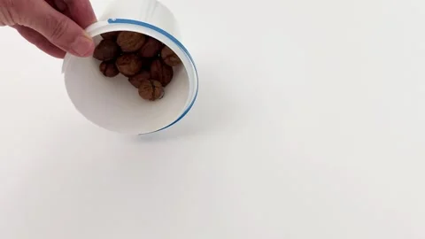 Cup of walnuts overturned on white backdrop, simple and tactile scene 스톡 동영상 321586787