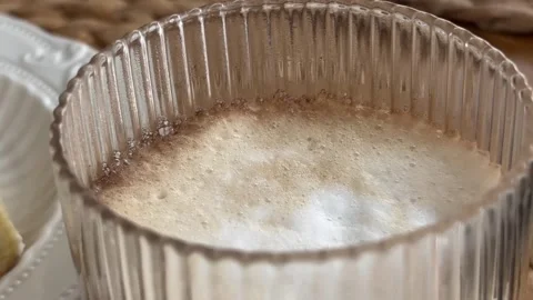 Cup of warm frothy coffee served with sweet dessert pastries on a table Stock Footage 341236205