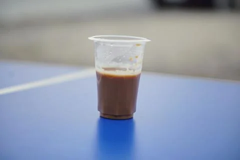 A cup of warm milk coffee or pulled tea in a transparent plastic cup on a blue Stock Photos