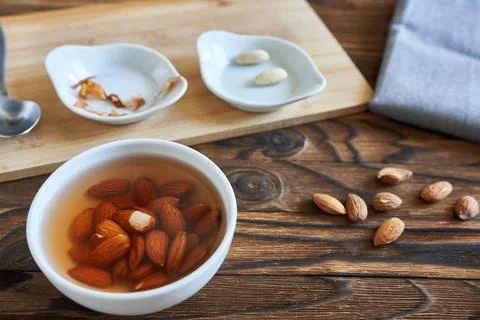 A cup of water and almonds. The process of peeling almonds. Stock Photos