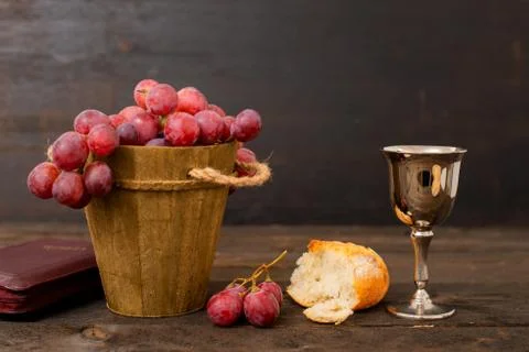 Cup with wine, bread, grapes and bible on wodd table Stock Photos