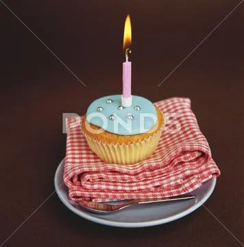 Cupcake With Blue Icing And A Candle