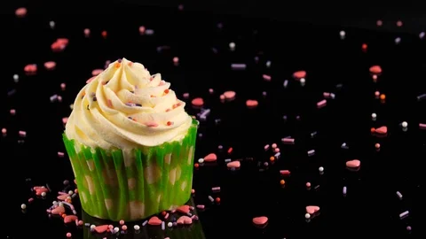 Cupcake, camera slow zoom in, black background decorated with sprinkles Vídeos de archivo 91030320