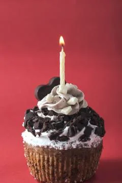 Cupcake with candle on red background Stock Photos