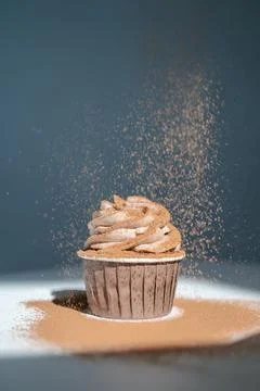 Cupcake on a dark background, which is sprinkled on top. Stock Photos