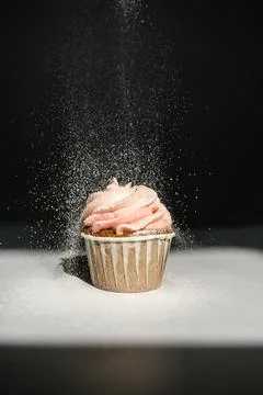 Cupcake on a dark background, which is sprinkled on top. Stock Photos