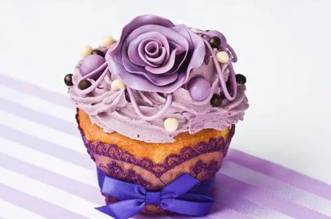 A cupcake decorated with purple sugar roses Stock Photos