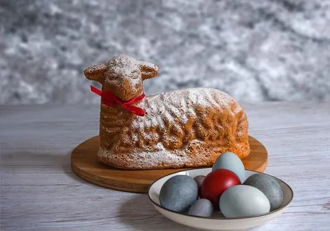 A cupcake in the form of the lamb of God for Easter with a plate of painted.. Stock Photos