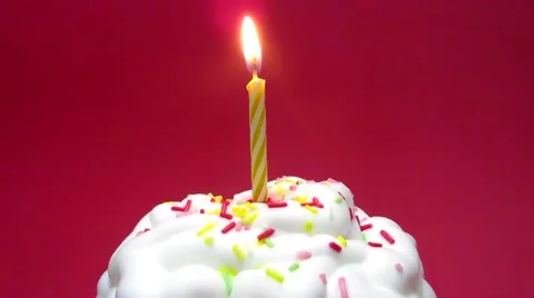 Cupcake with a lit candle over red background Stock Footage 54605562