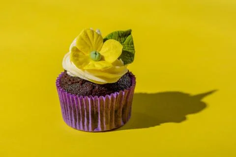 Cupcake in purple wrap on solid yellow background with strong shadow. Pop art Foto stock