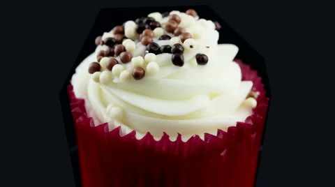 Cupcake with white and dark candy topping rotating against black background Stock Footage 49905418