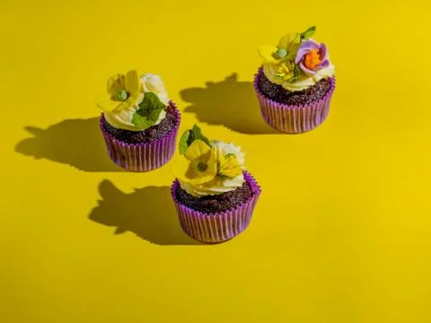 Cupcakes in purple wrap on solid yellow background with strong shadow. Pop ar 写真素材