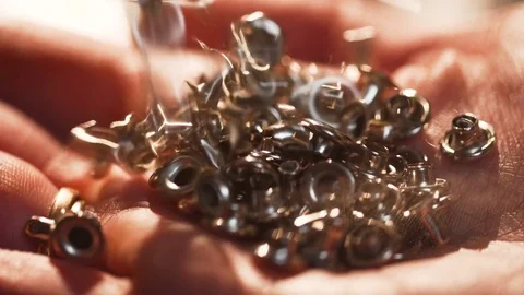 Cupped female hand of metallic rivets shining under the lamp light during Video stock 77413989