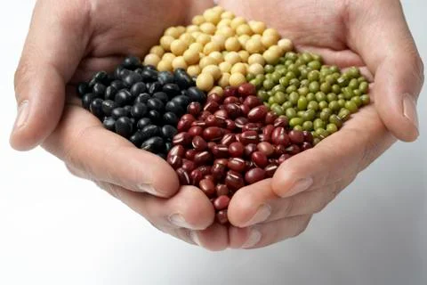 Cupped hands holding multicolored beans and legumes Stockfoto's