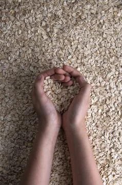 Cupped hands with rolled oats in shape of heart Stock Photos