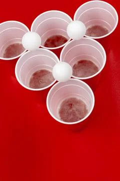 Cups and plastic ball on red background. Beer pong game Foto stock