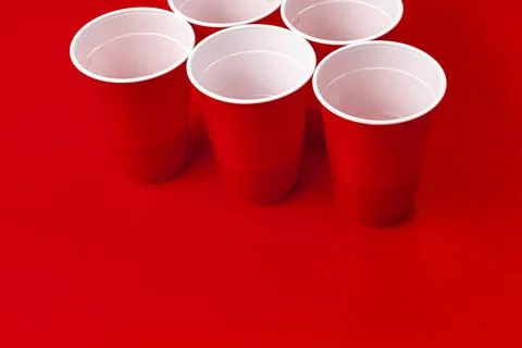Cups and plastic ball on red background. Beer pong game Foto stock