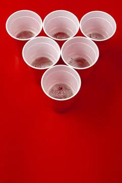 Cups and plastic ball on red background. Beer pong game Foto stock