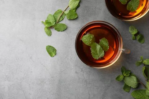 Cups of aromatic herbal tea with mint on grey table, flat lay. Space for text Stock Photos