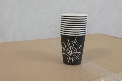 Cups with a spider web design are stacked neatly on a cardboard box in an ind Stock Photos
