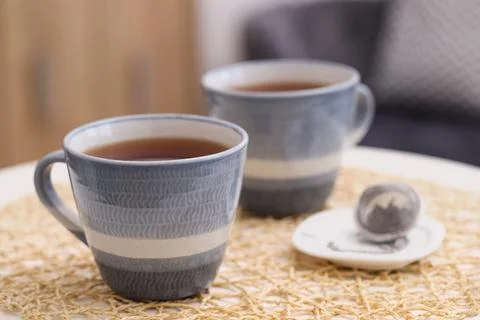 Cups of tea and snap infuser with dry leaves on table indoors, closeup. Spa.. Stock Photos