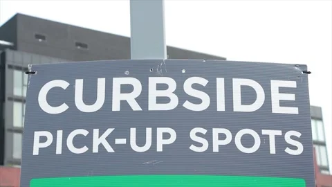 Curbside pick up spots sign on post with building and sky in background Vídeo Stock 248712310