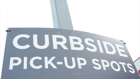 Curbside pick up spots sign on post with building and sky in background Stock Footage 248712312