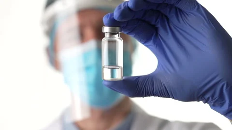 Cure. Close up of a vial of vaccine in the center of the frame. Male doctor in Stock Footage 147961553