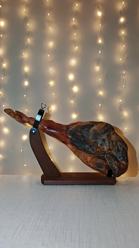 Cured jamon serrano on holder as festive table element with blurred garlands. Stock Footage 324925509