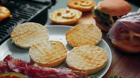 Cured meat positioned over sauced burger buns, 4K Stock Footage 341117651
