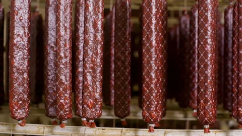 Cured sausages maturing on racks on meat production in meat shop of factory. Stock Footage 246403875