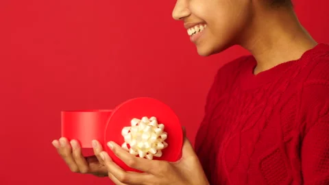 Curiosity. Side view of young mixed race girl opening small gift box with ribbon Stock Footage 146127945
