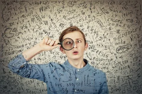 Curious, addicted boy seeking for correct answer as looks through the magnify Foto stock
