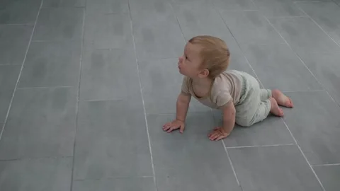 Curious baby crawling on gray tile Stock Footage 336073999