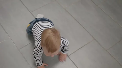 Curious baby crawling on gray tile floor Stock Footage 337738662
