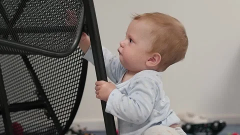 Curious Baby Joyfully Exploring the Room with a Chair Stock Footage 304998665