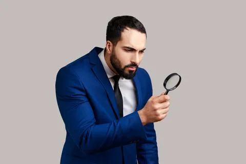 Curious bearded man looking through magnifying glass, finding out something Foto stock