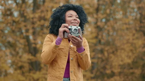Curious beautiful colored lady taking pictures of golden autumn on camera Stock Footage 254283676