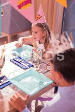 Curious birthday girl smiling and waiting for food at the party Stock Photos