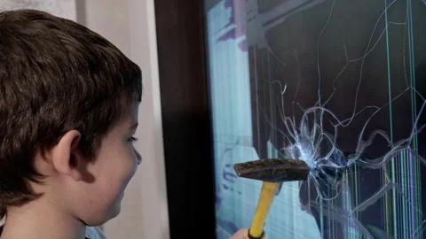 A Curious Boy Examining a Shattered TV Screen with a Hammer in His Hands Stock-Footage 257578759