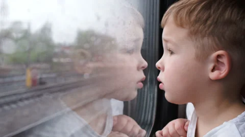 Curious boy looking out of the train window in rainy weather Stock Footage 39794050