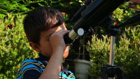 Curious boy looking through telescope eyepiece at the sky Stock Footage 309458679