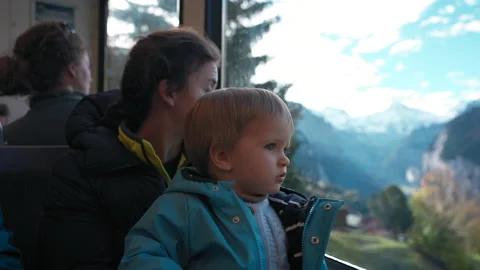 Curious boy looks out window of train sitting on mom lap Stock Footage 228857034