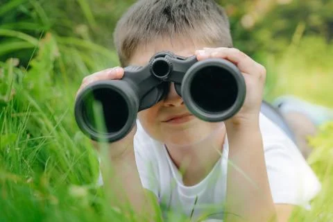 Curious boy looks for wildlife through binoculars in the park. Exploring the  Stock Photos