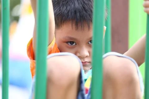 Curious Boy at Playground Looking Through Bars Stock Photos