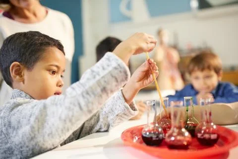 Curious boy using pipette in beaker at interactive exhibit in science center Stock Photos